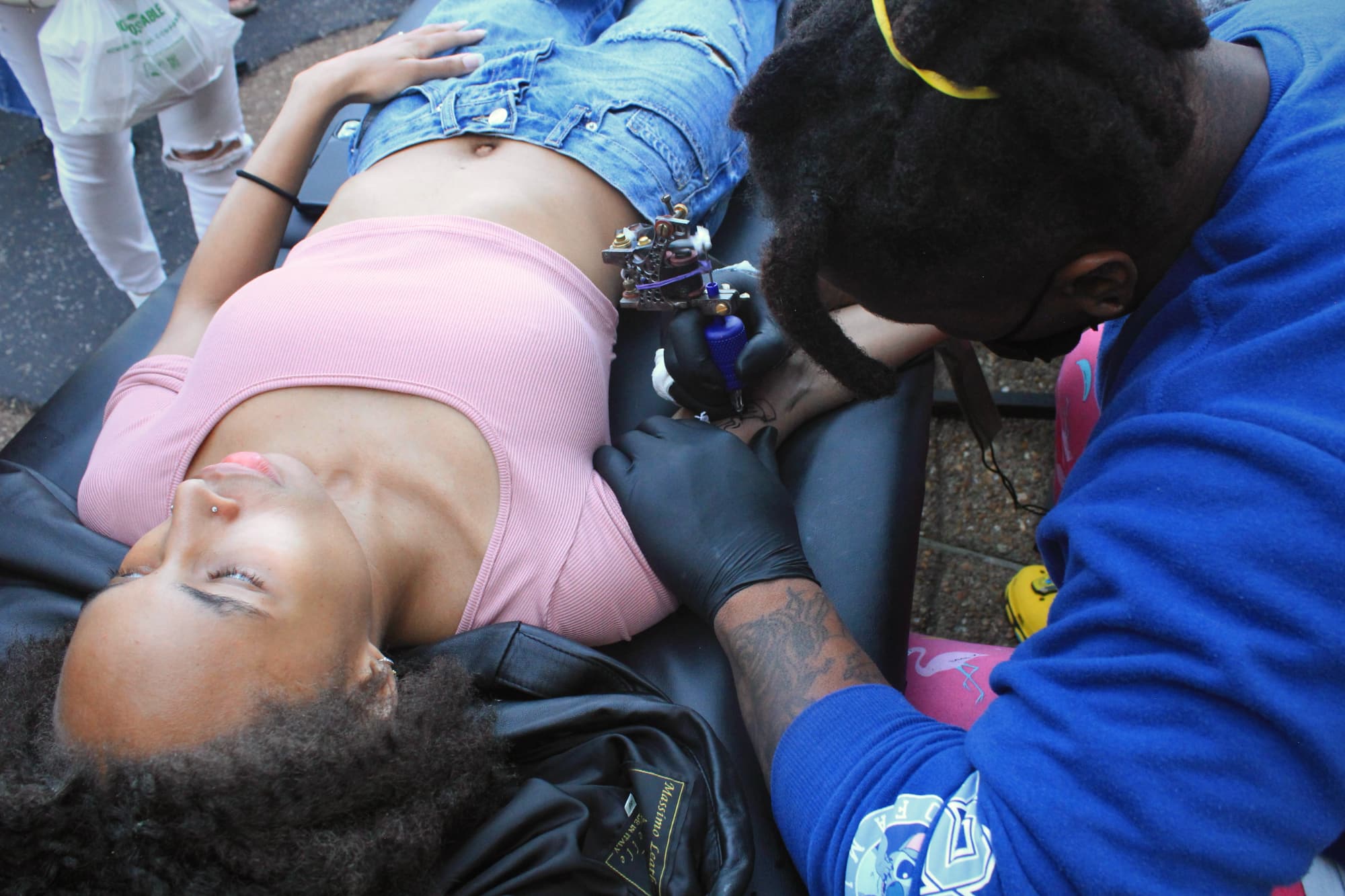 Person getting a tattoo on their arm outdoors.