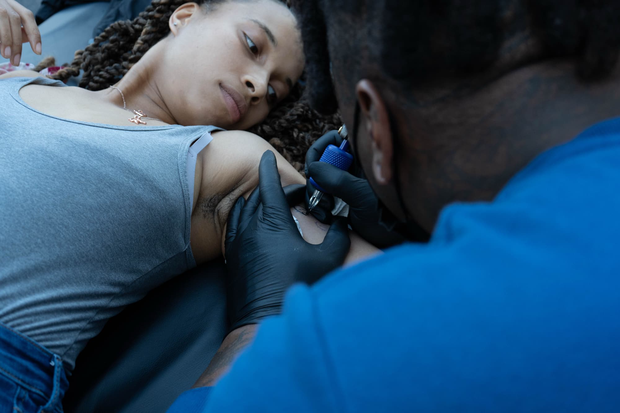 Person receiving tattoo on upper arm.