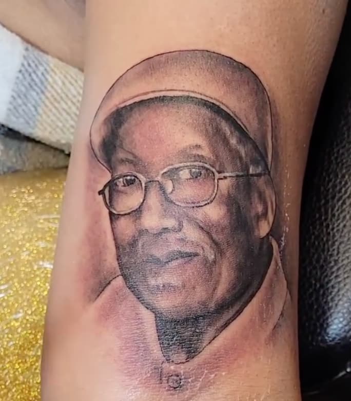 Realism tattoo of elderly man wearing glasses and hat.
