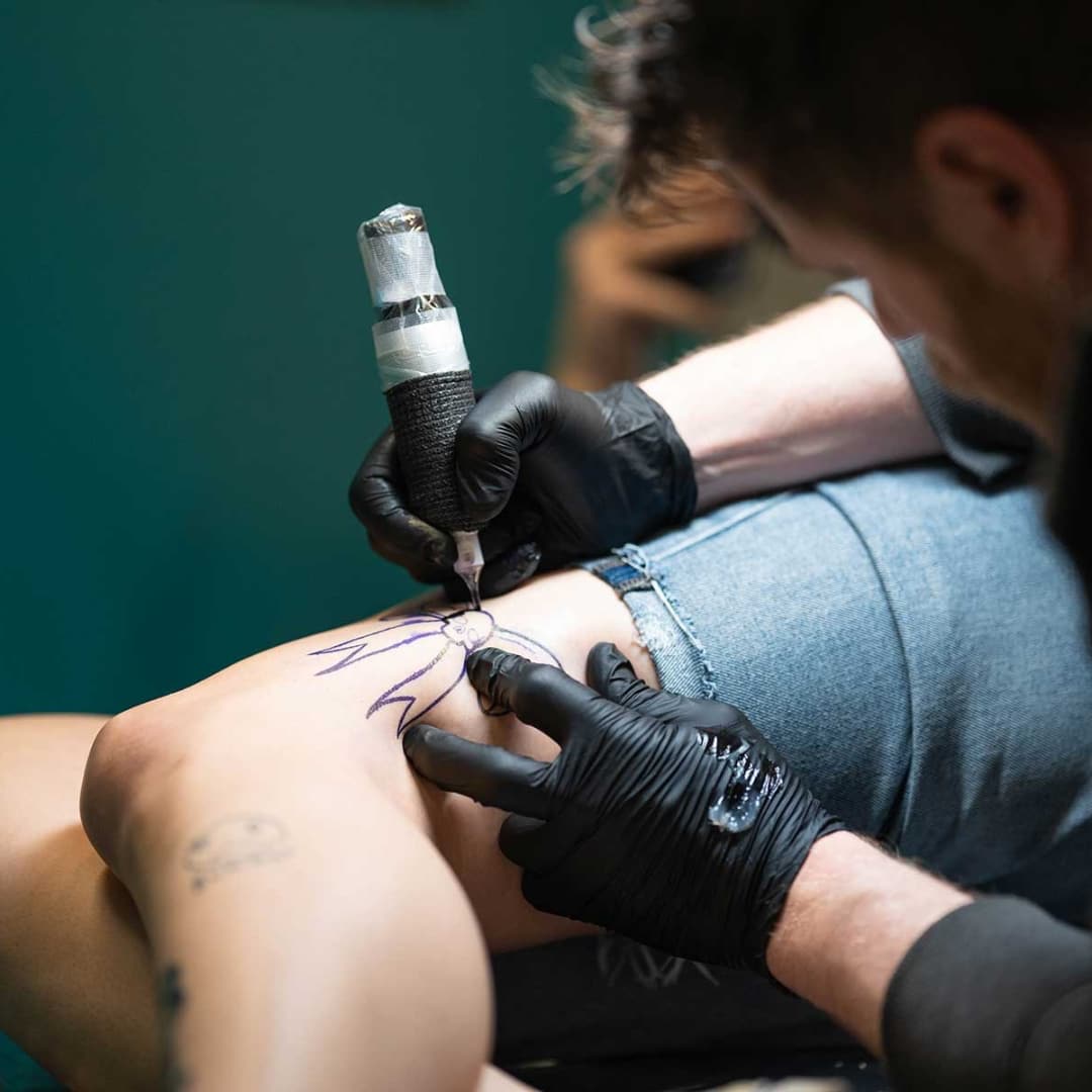 Tattoo artist drawing design on knee