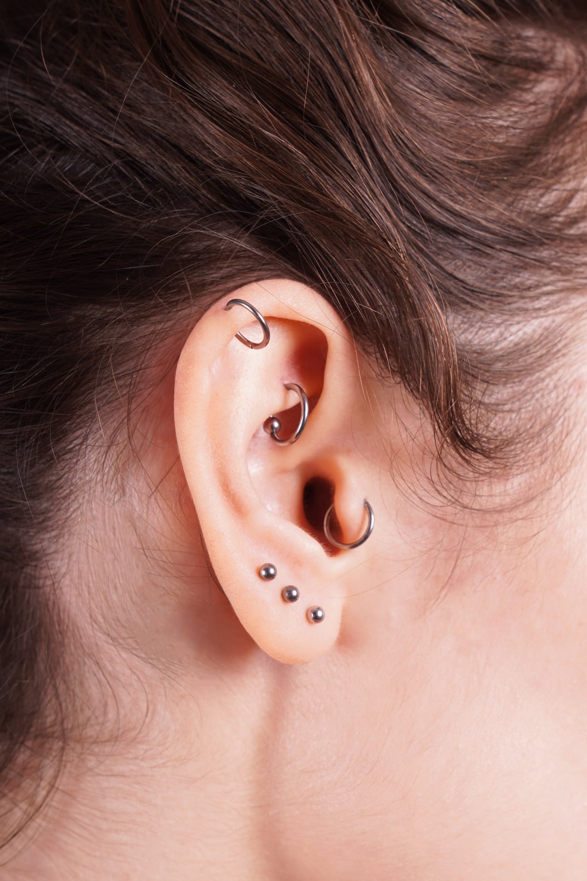 Close-up of an ear with helix, rook, tragus and lobe piercings